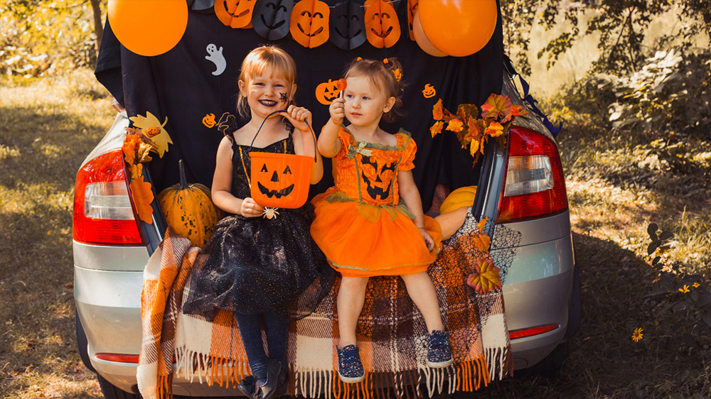 Two trick-or-treaters smiling in costume for Halloween.